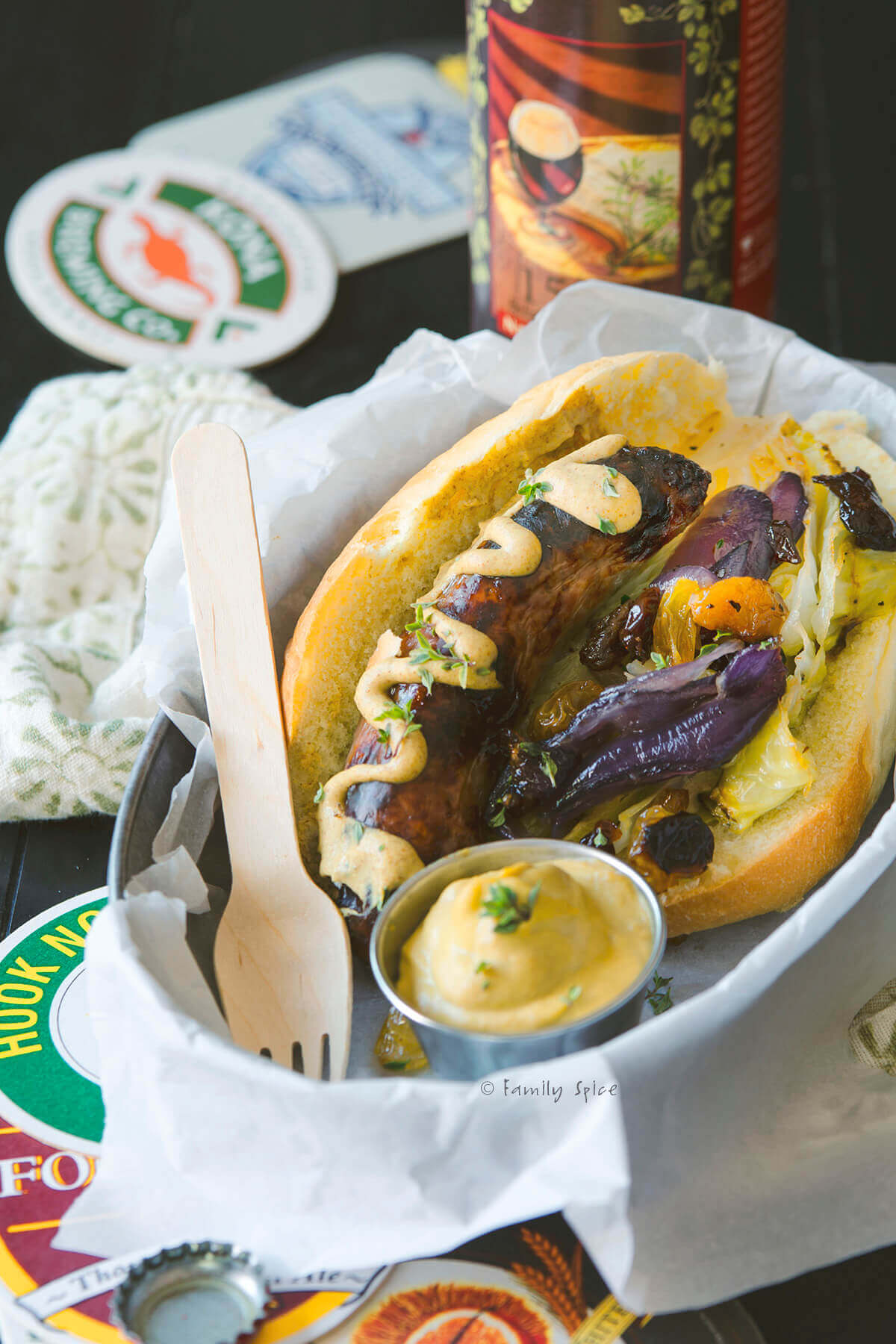 Oven baked bratwurst on a hoagie with mustard, roasted cabbage and red onions in a hoagie roll and in a metal food basket