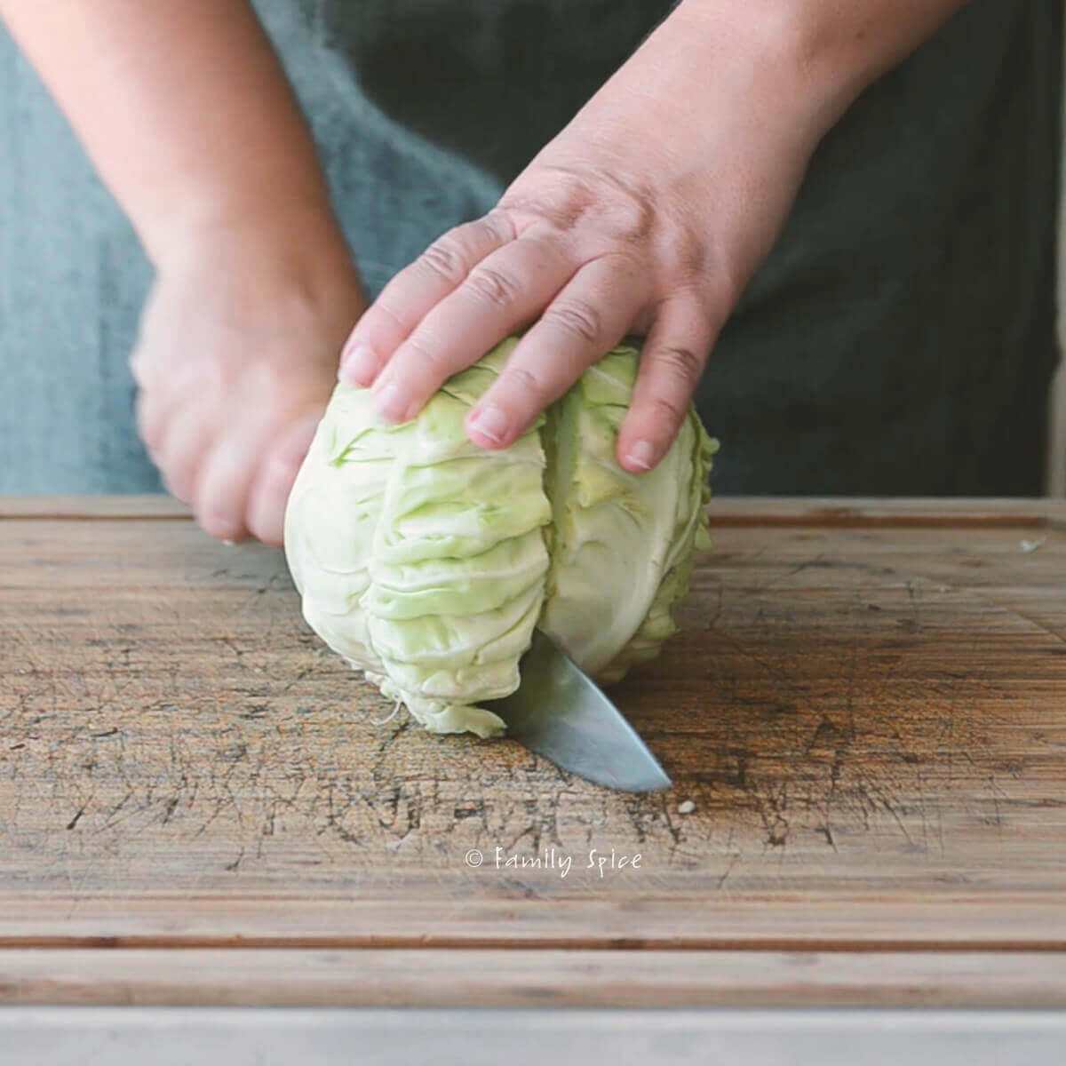 Cutting a green cabbage in half on a wooden cutting board
