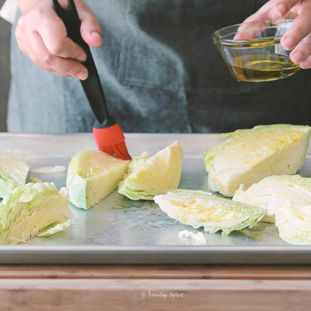 Brushing wedges of cabbage with olive oil on a baking sheet