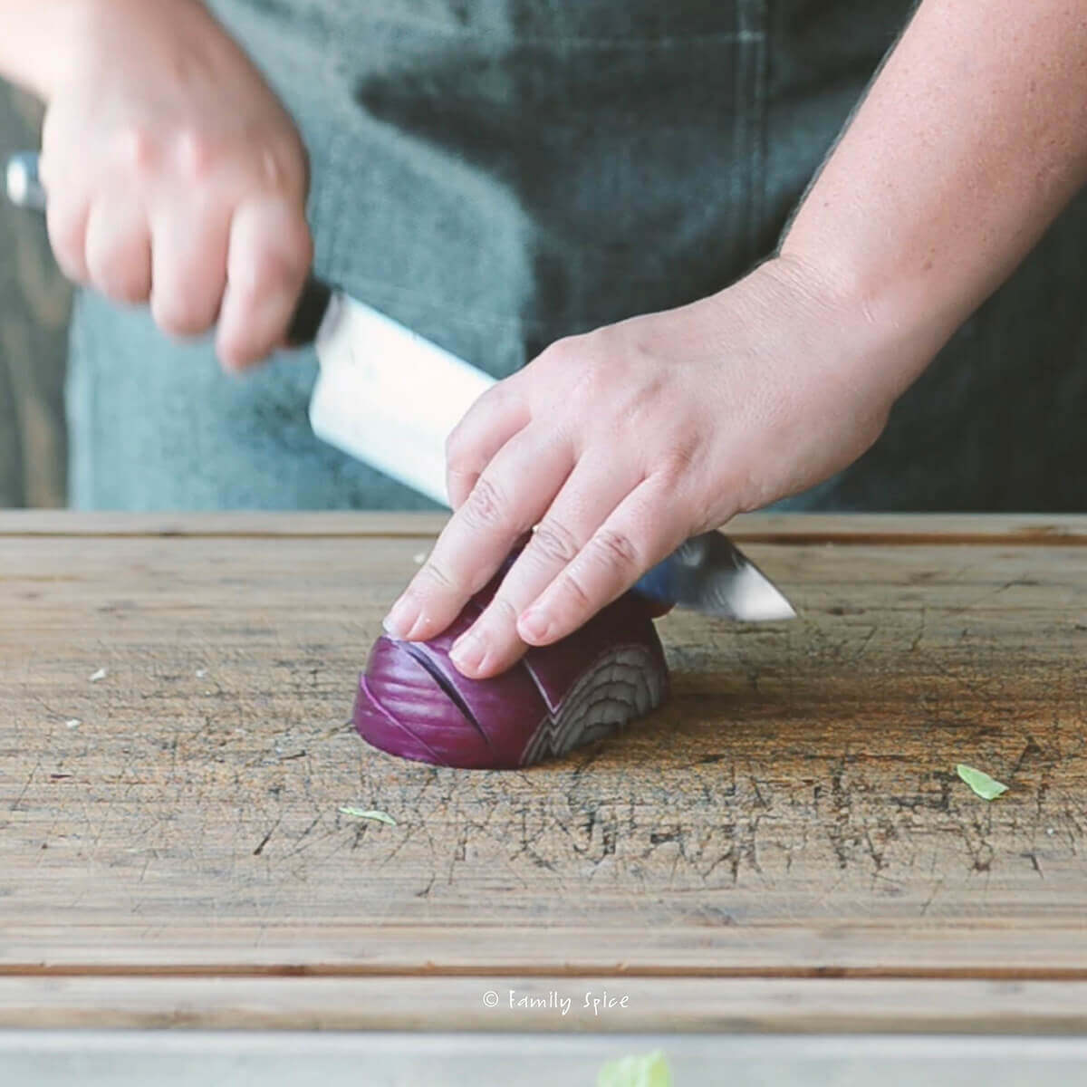 Cutting a red onion into wedges on a wooden cutting board