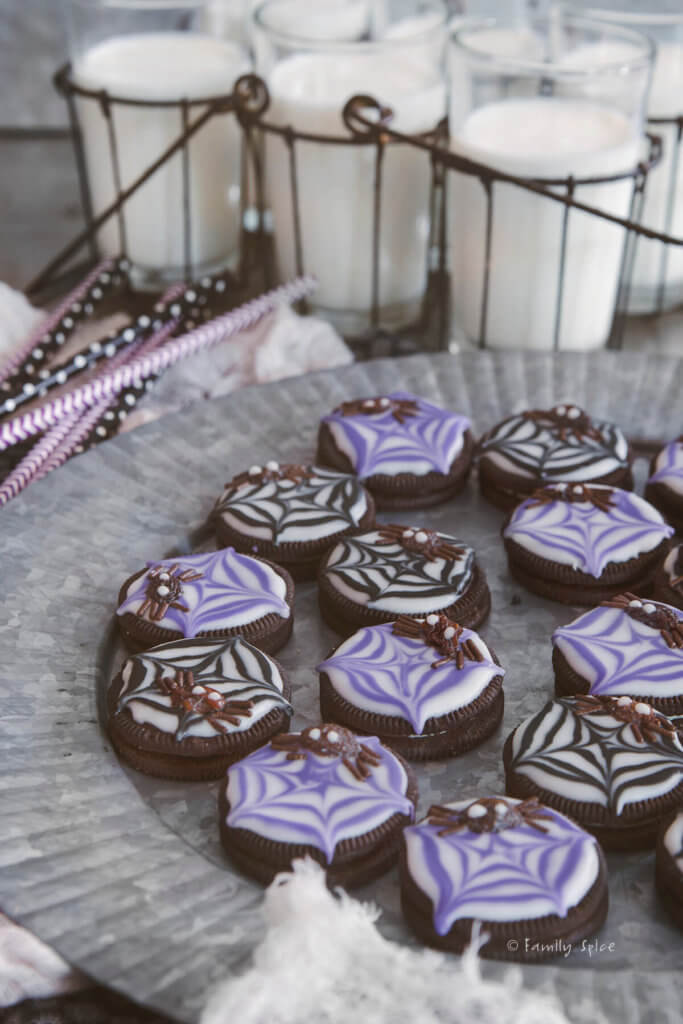 Side view of black and purple raisin spider cookies on a tray