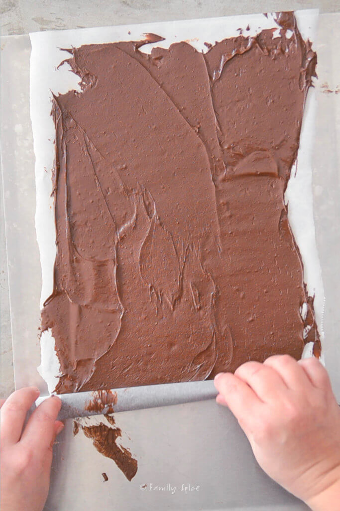 Rolling up a sheet of parchment paper spread with melted chocolate