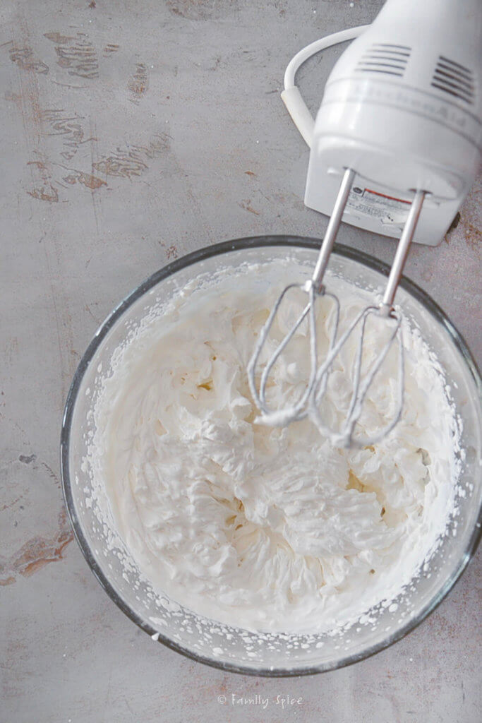 Making homemade whipped cream in a bowl with hand mixer