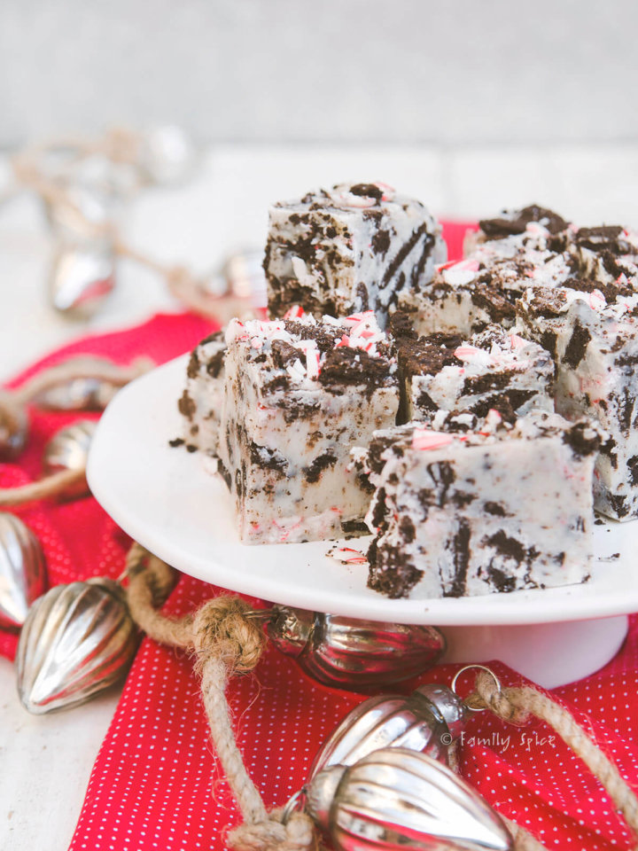 A white cake stand with several cubes of peppermint oreo fudge