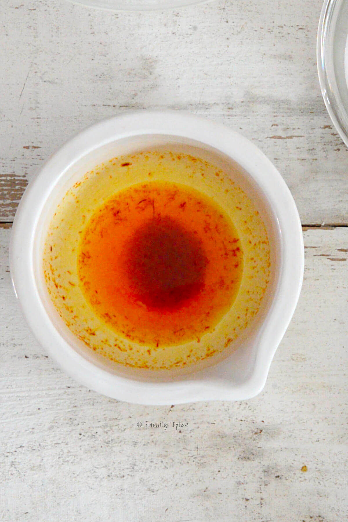 Top view of ground saffron blooming in hot water in a white mortar and pestle