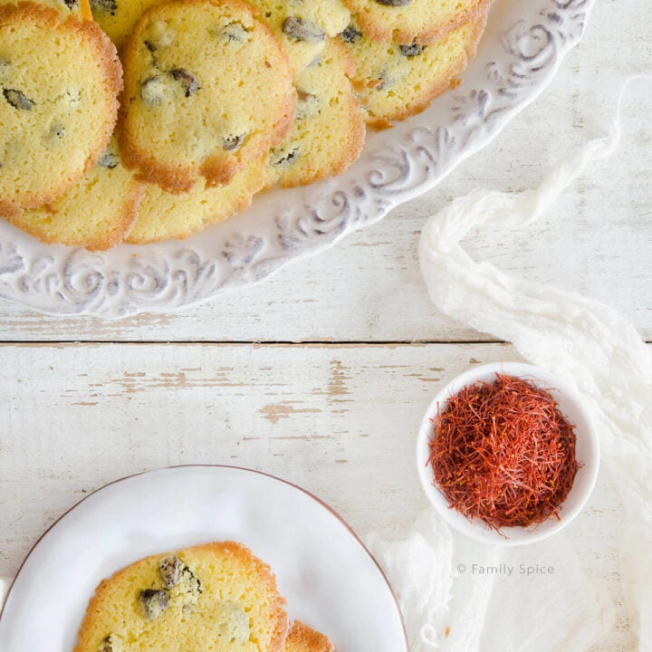 Overhead view of a platter of Persian Saffron Raisin Cookies (shirini kishmishi) with a bowl of saffron and a small plate of cookies
