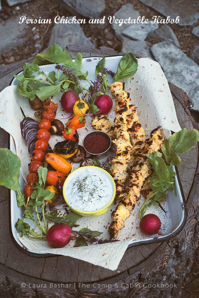A tray of chicken kebab and vegetables on a stone step