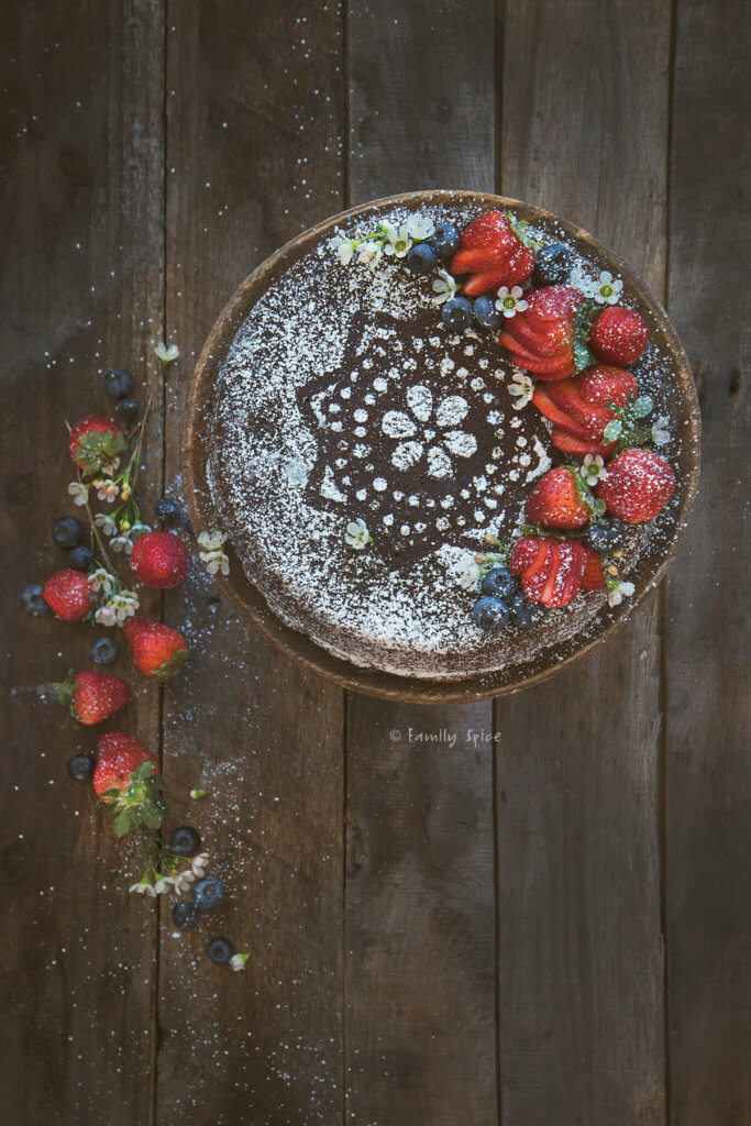 A gingerbread cake dusted with powdered sugar and topped with berries