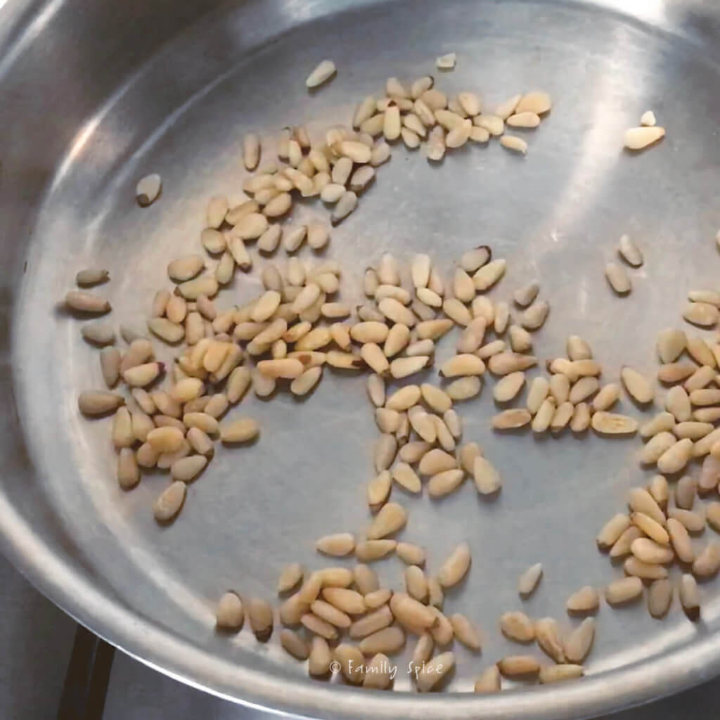 Toasting pine nuts in a stainless steel pan