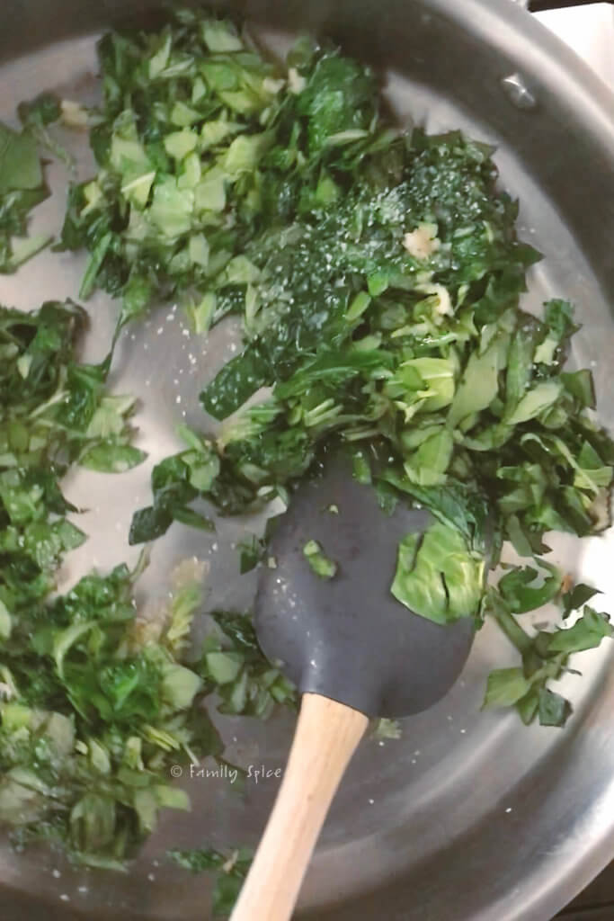 Sautéing garlic, spinach and basil in a stainless steel pan