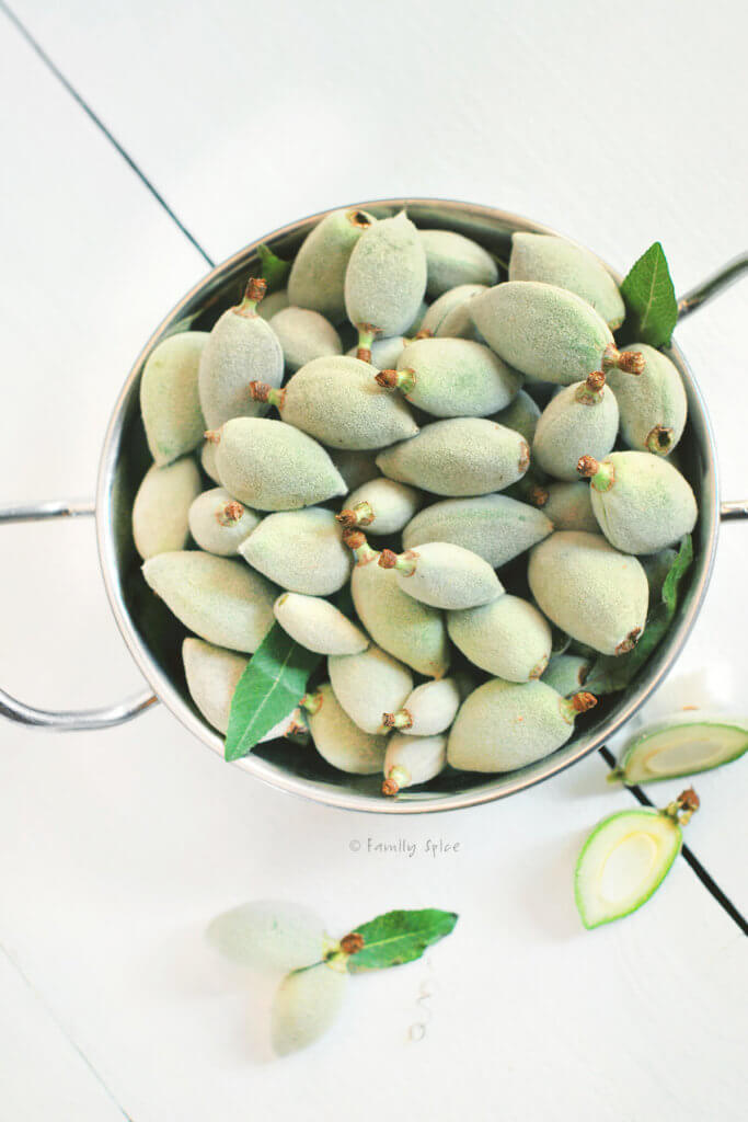 Top view of a metal bowl full of green almonds, chaghaleh badoom