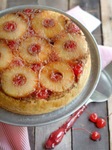 Closeup of the top of a freshly baked pineapple upside down cake on a metal cake stand.