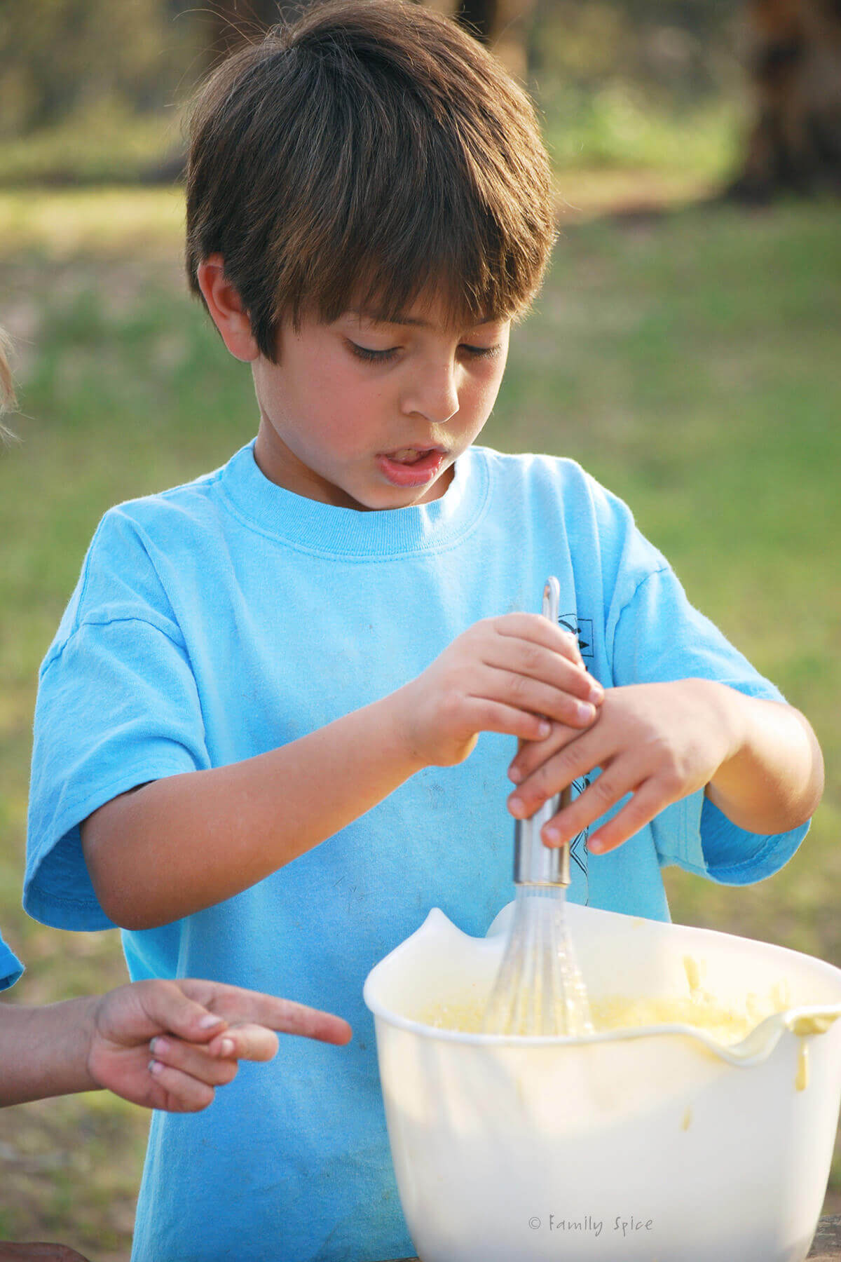My son as a cub scout mixing up cake batter at a campsite