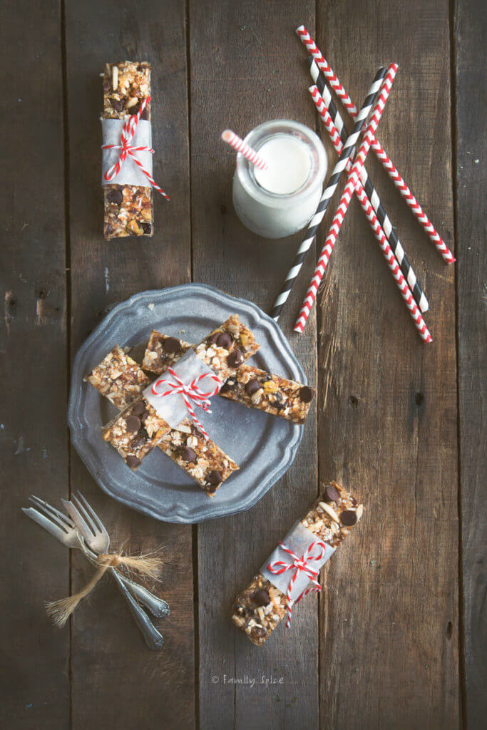 Top view of several oatmeal date nut bars wrapped in a strip of parchment paper and tied with bakers twine with a glass bottle of milk next to it