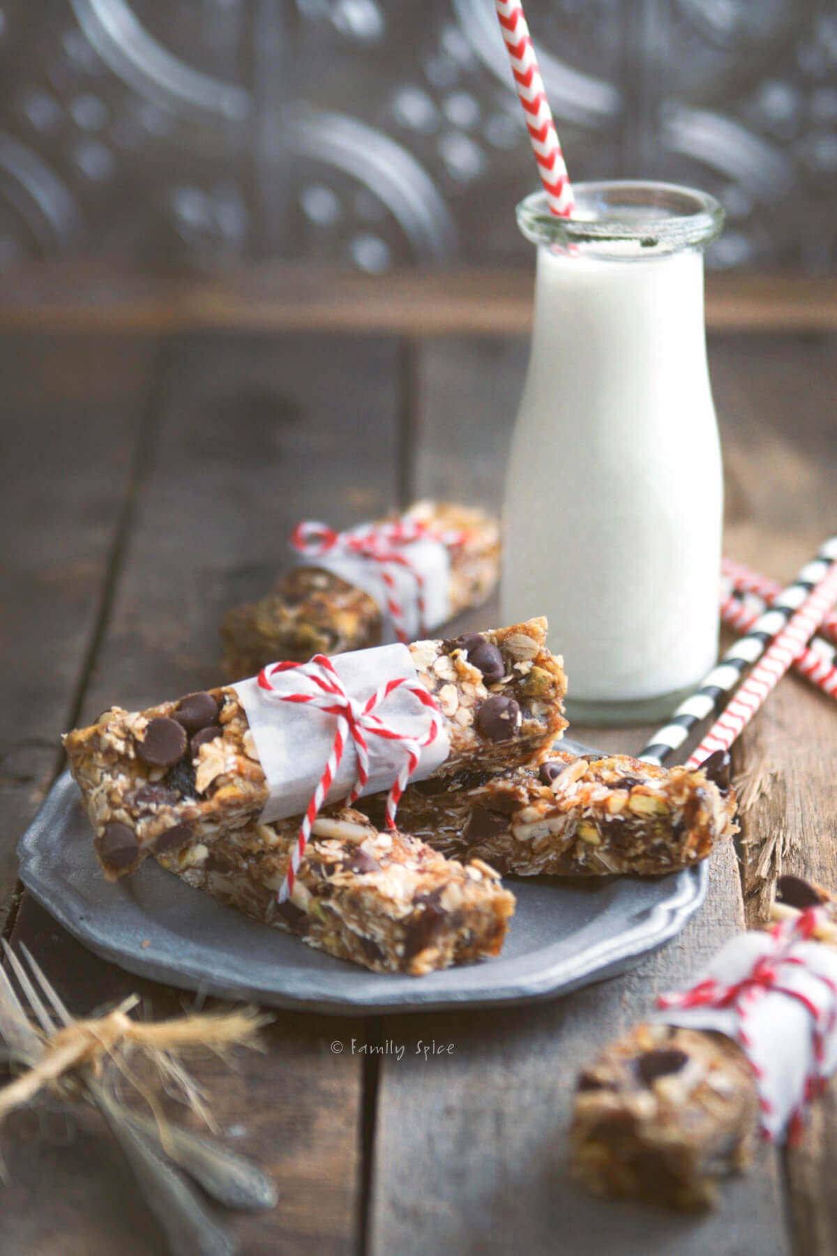 Oatmeal date nut bars wrapped in a strip of parchment paper and tied with bakers twine with a glass bottle of milk next to it