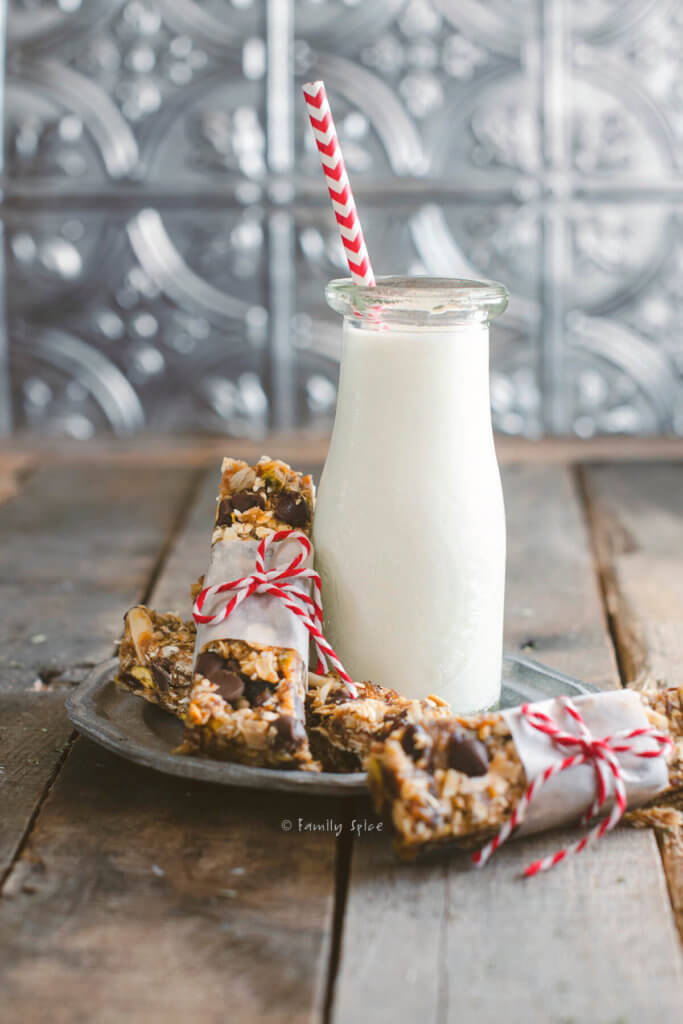 Oatmeal date nut bars wrapped in a strip of parchment paper and tied with bakers twine with one bar leaning on a glass bottle of milk