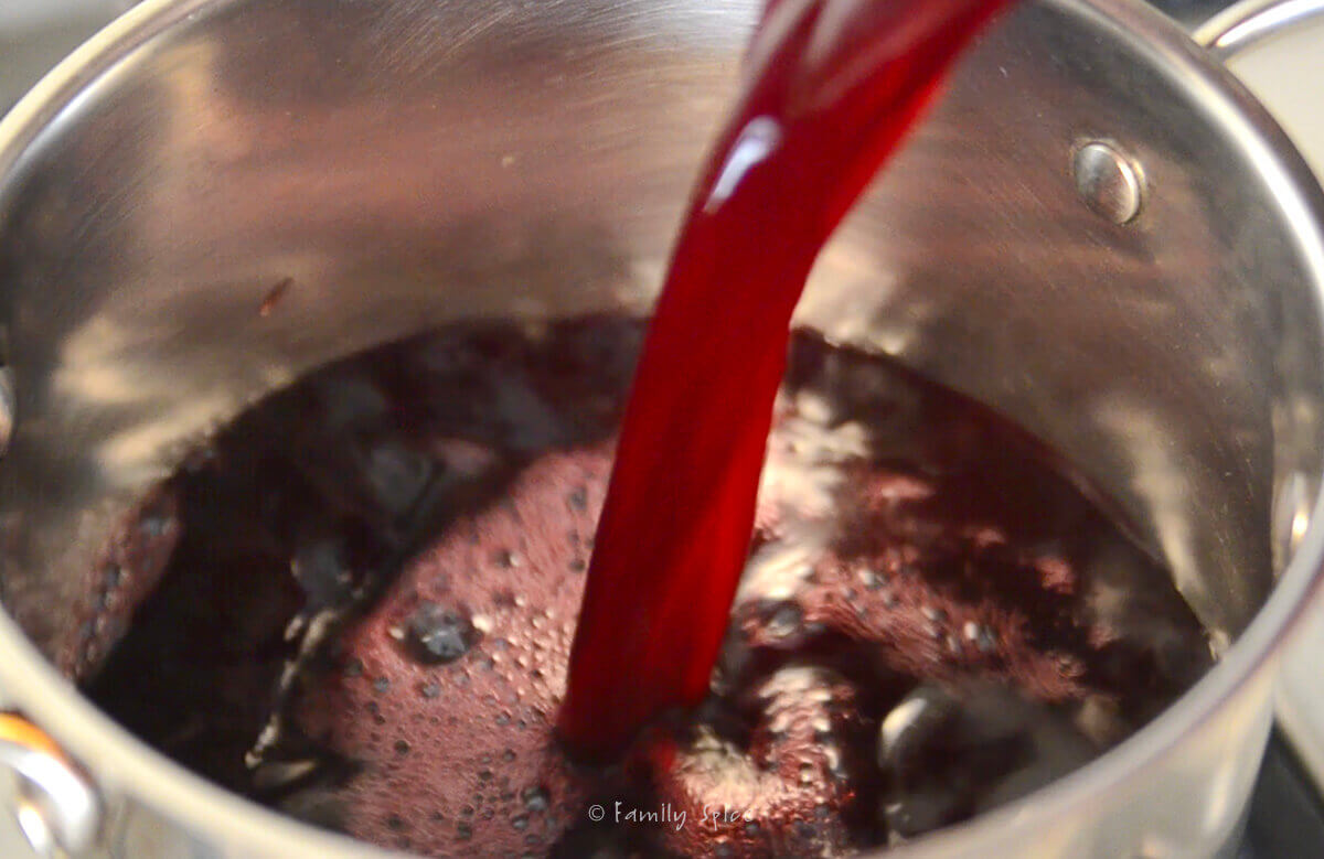 Pouring pomegranate juice into a stainless steel pot