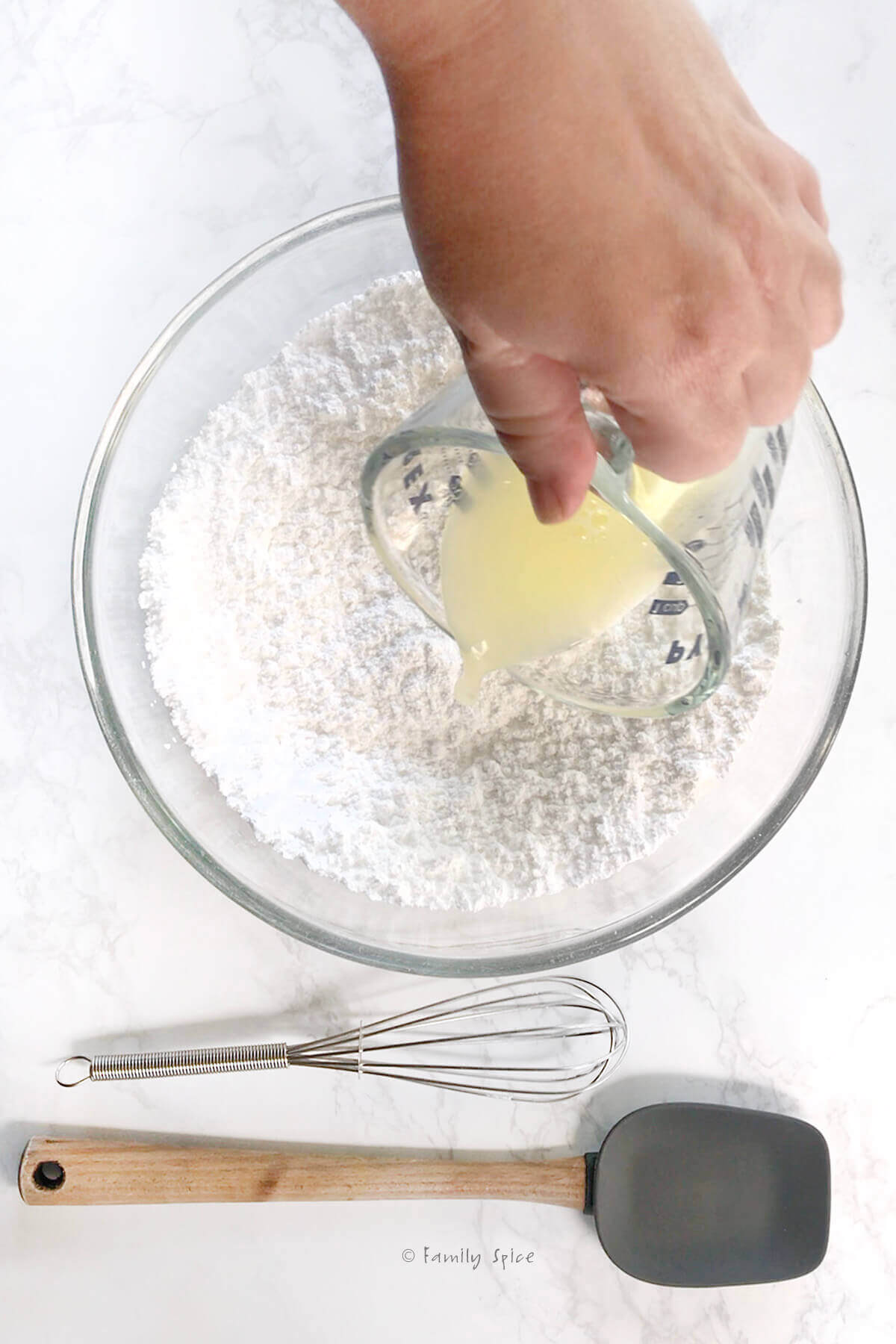 Pouring egg whites into a bowl with powdered sugar