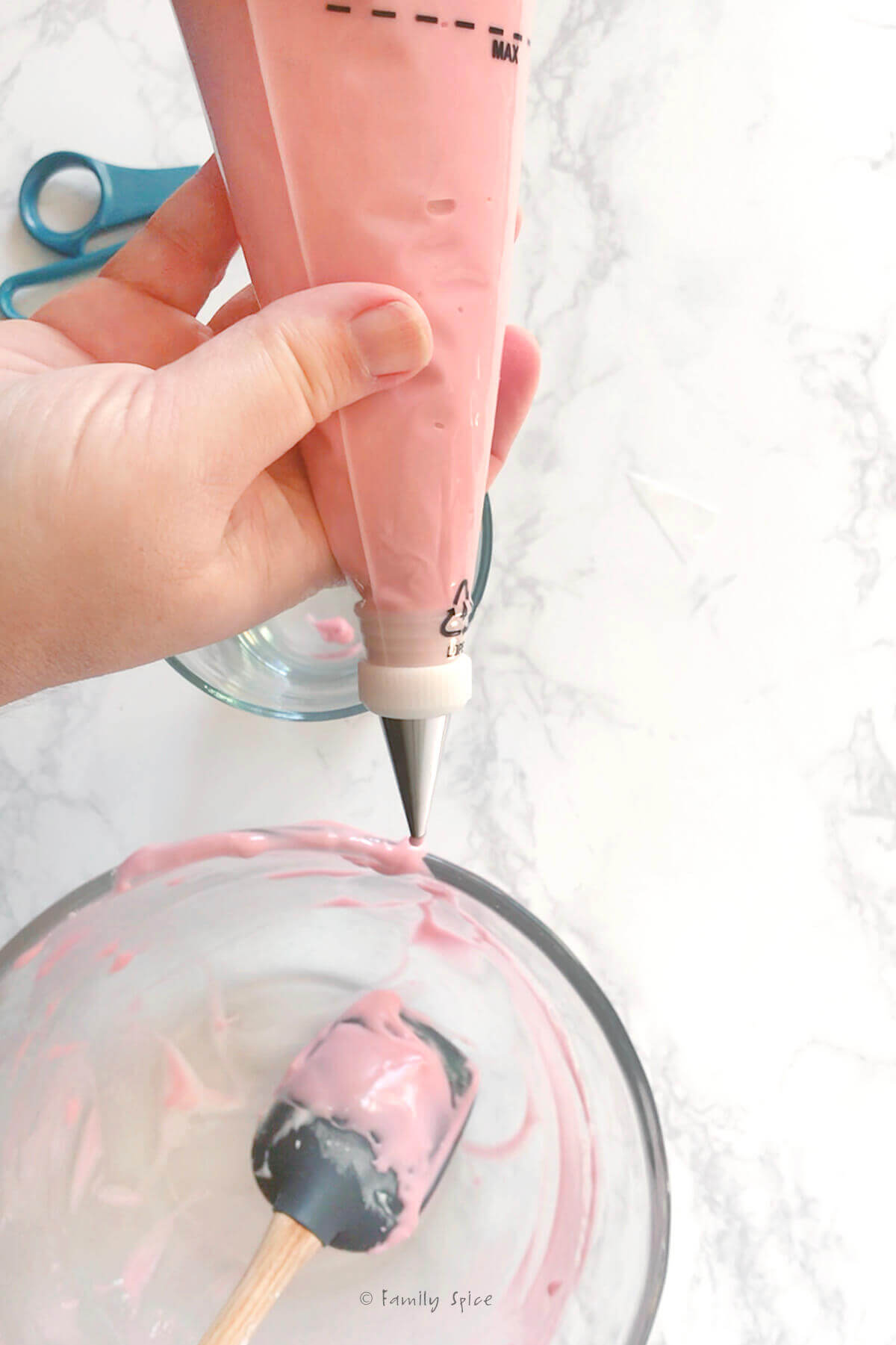 A hand holding pink icing in a piping bag