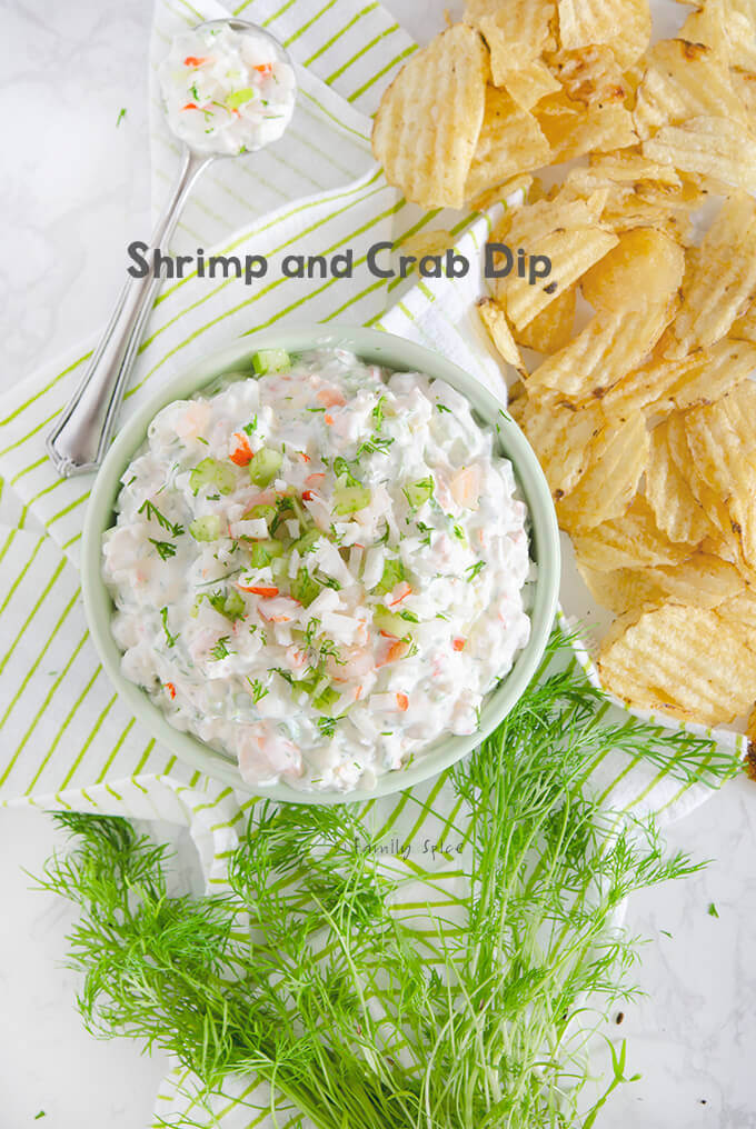 Closeup of overhead shot of a bowl of shrimp and crab dip with fresh dill and potato chips scattered around it by FamilySpice.com