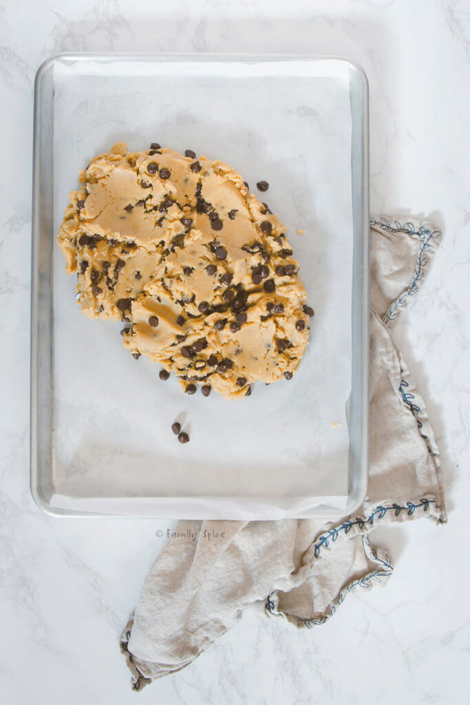 Chocolate chip cookie dough dumped into sheet pan