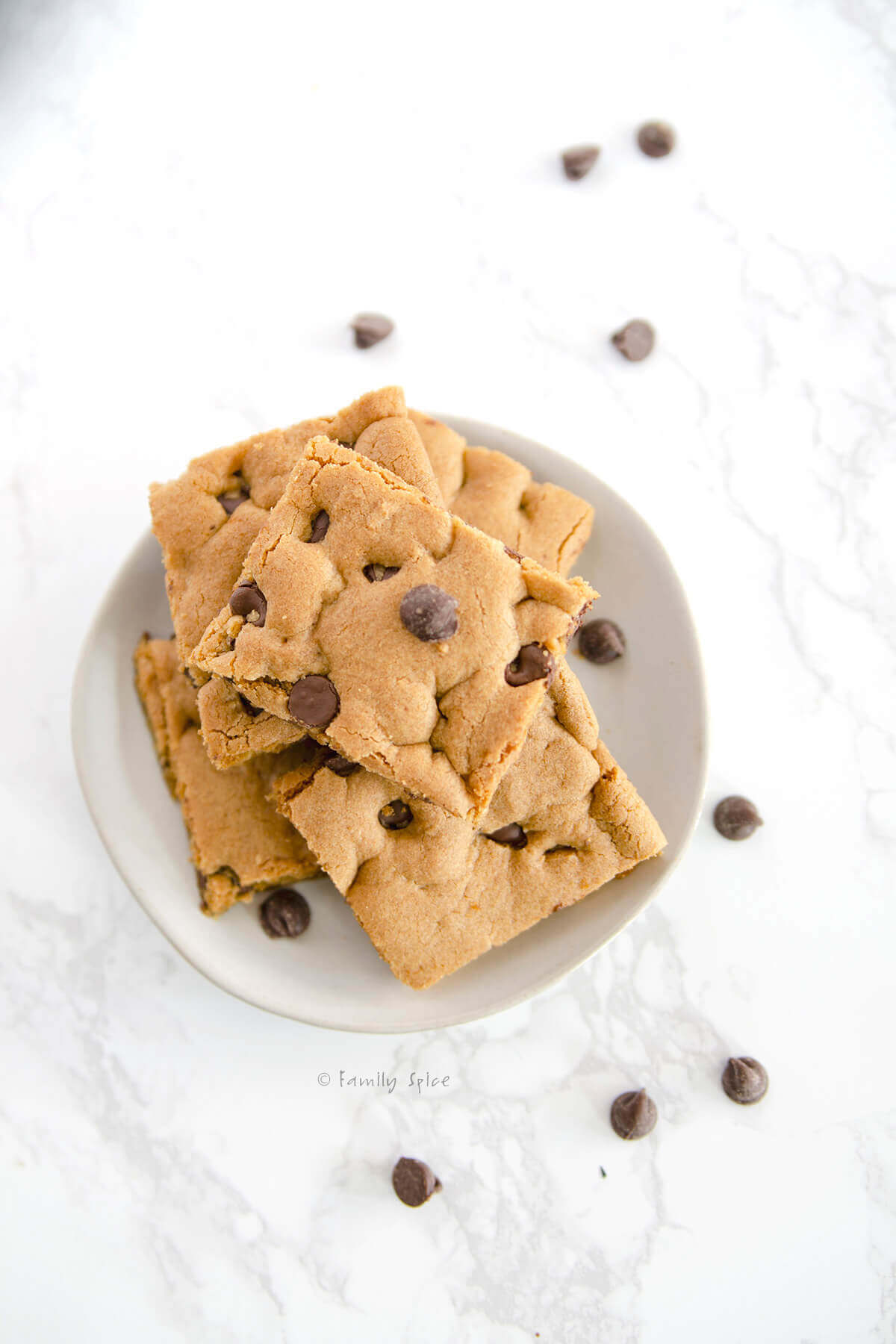 Top view of a small white plate with a stack of chocolate chip cookie bars