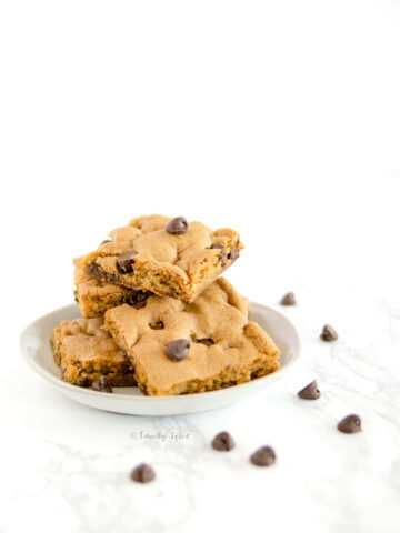 Side view of a small white plate with a stack of chocolate chip cookie bars