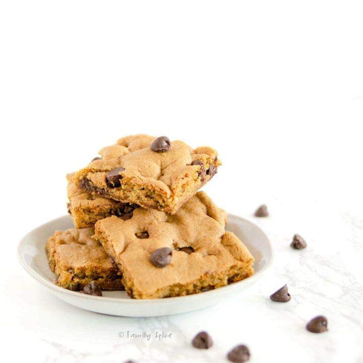 Side view of a small white plate with a stack of chocolate chip cookie bars