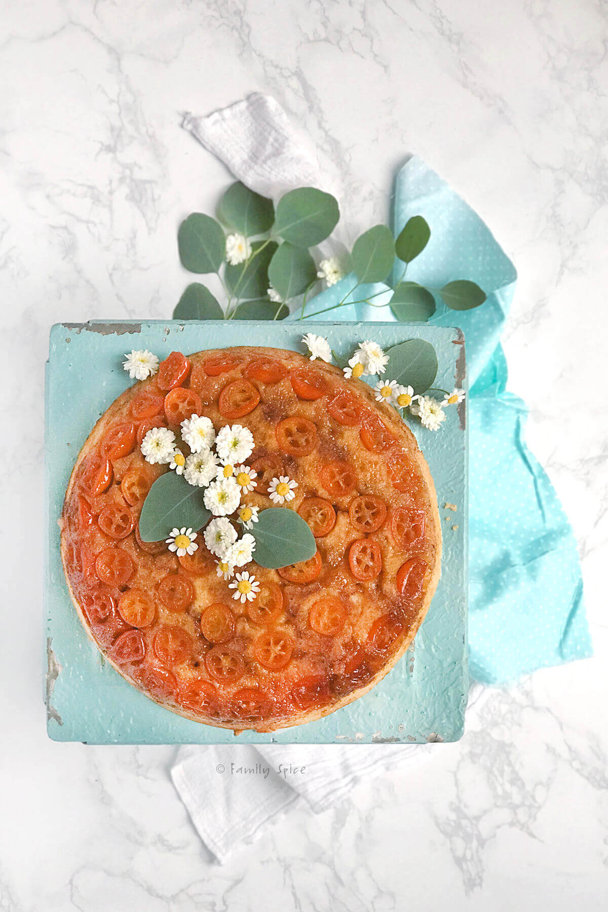 Overhead shot of kumquat upside down cake garnished with flowers 