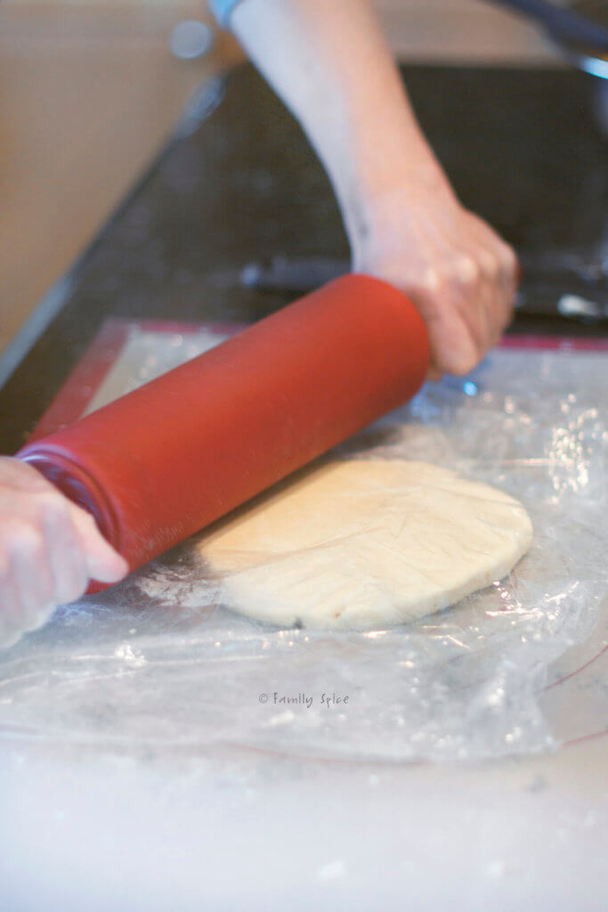 Rolling pie dough between two sheets of plastic wrap