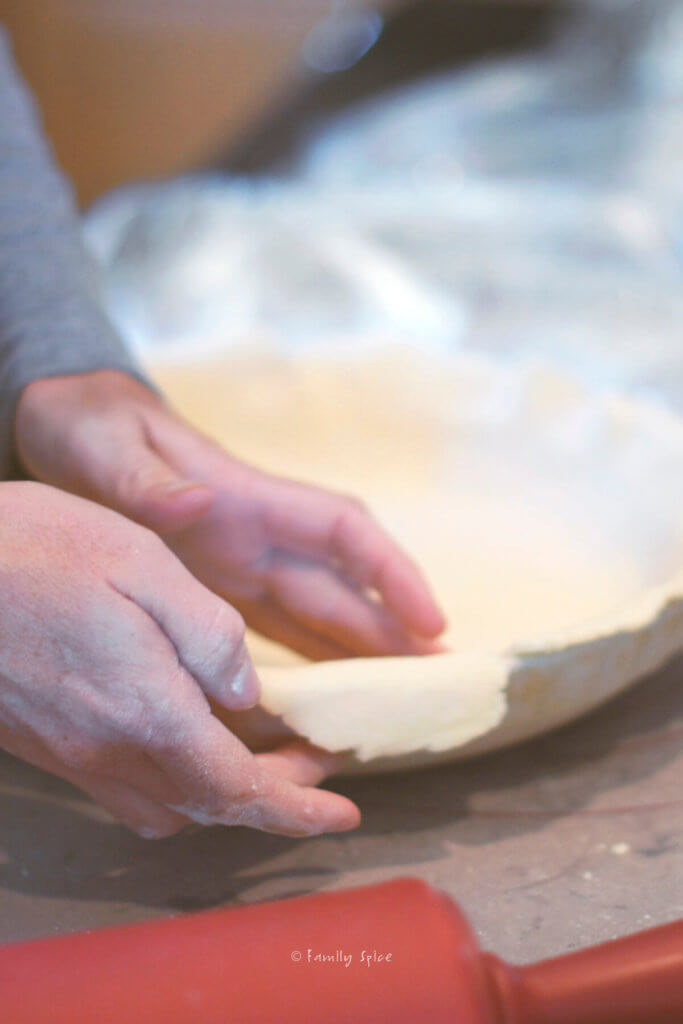 Placing pie dough and pressing into a pie dish