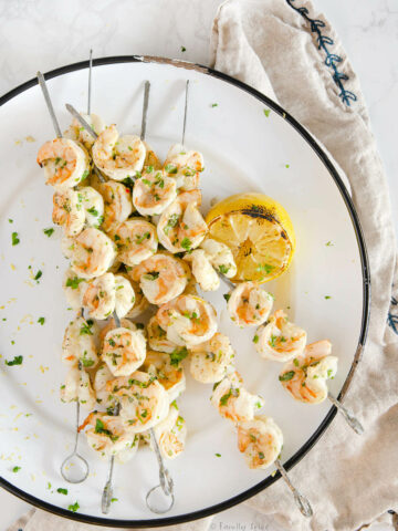 Closeup of a white enamel platter with grilled shrimp kabobs on it