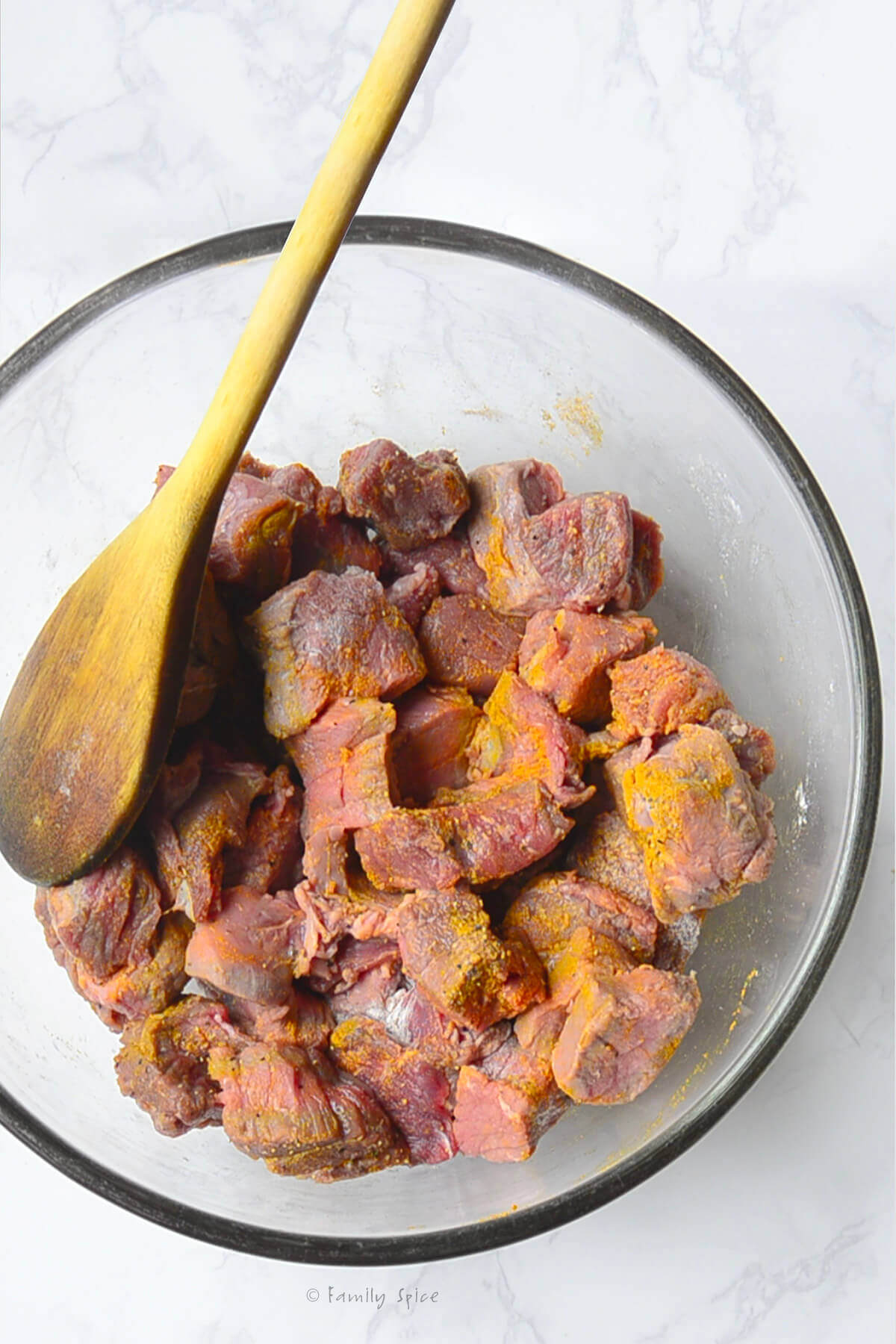 Beef stew meat in a mixing bowl and seasoned with salt, pepper and turmeric