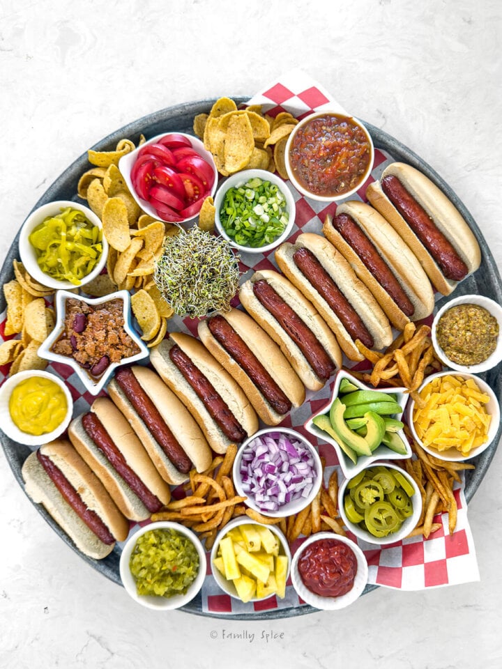 Top view of a tray showing hot dogs and lots of toppings for a hot dog board.