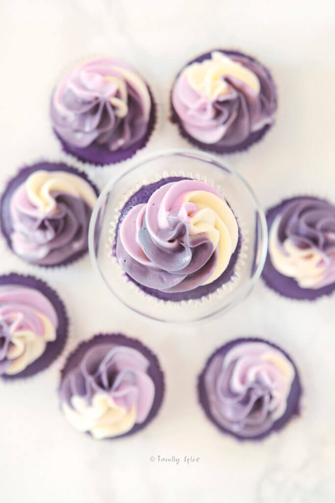 Top view of one purple grape kool aid cupcake with purple swirl frosting on top and more cupcakes around it