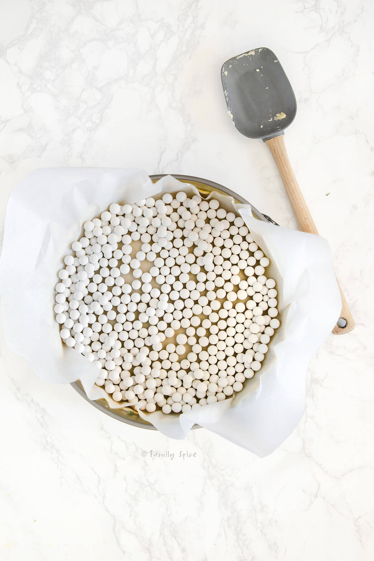 Pie crust pressed into a springform pan with parchment paper and pie weights over it