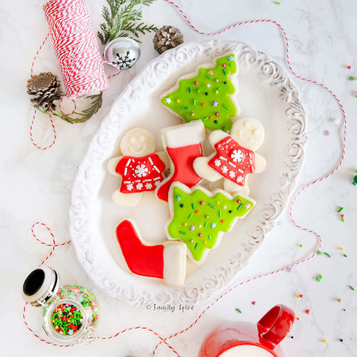 Top view of Christmas themed sugar cookies on a white plate by FamilySpice.com