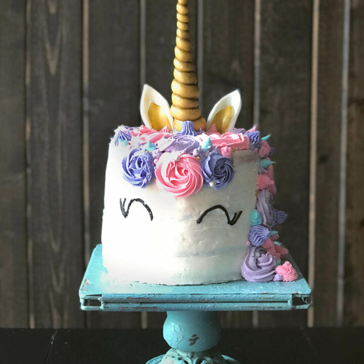 A unicorn cake decorated with gold, pink, lilac and aqua blue