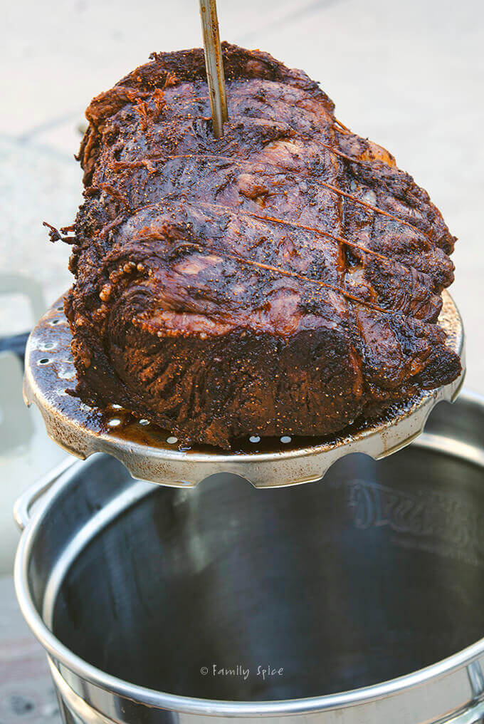 A crispy rib roast tied with kitchen twine taken out of the deep fryer by FamilySpice.com