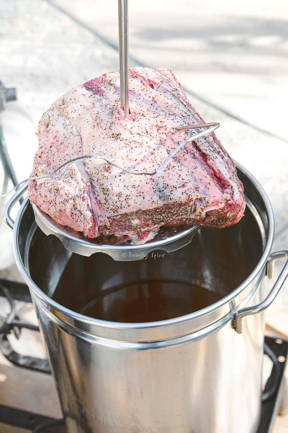 A seasoned rib roast ready to be lowered in the hot oil of a deep fryer