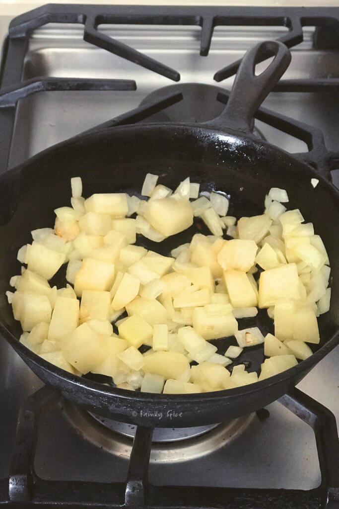 Cooking potatoes and onions in a cast iron pan