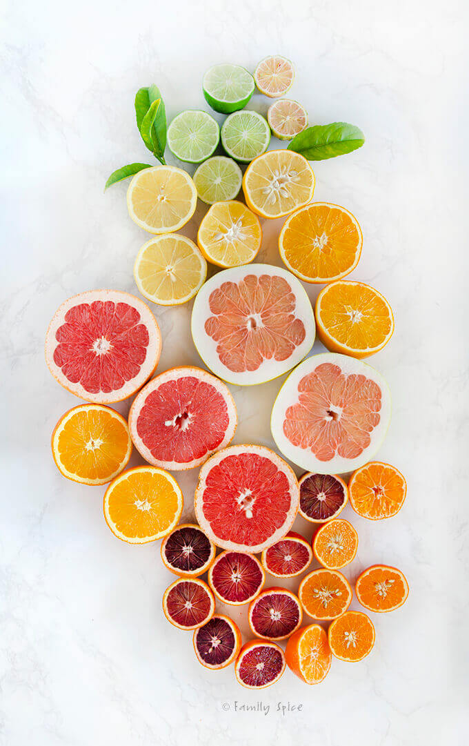 Overhead shot of an assortment of citrus fruits cut in half: limes, lemons, oranges, tangerines, grapefruit, pomelo and blood oranges by FamilySpice.com