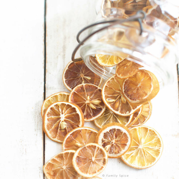 A large glass mason jar tipped over with oven dried lemon slices spilling out