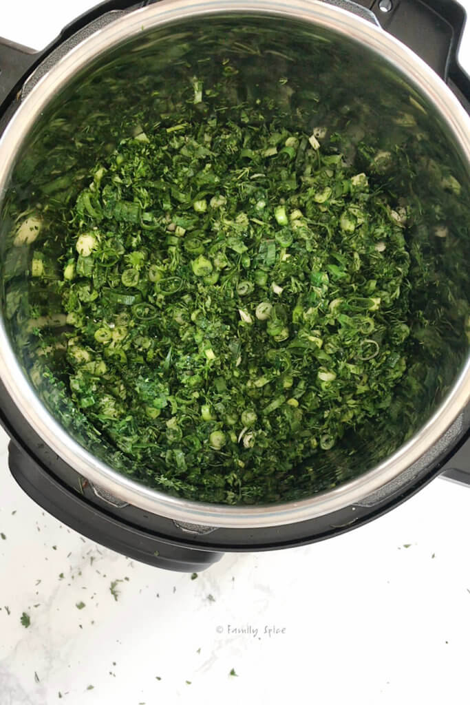 Satuéing chopped green herbs in the instant pot