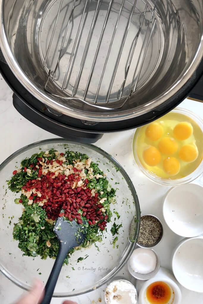 A glass bowl with sautéed herbs and other ingredients added with an instant pot and more ingredients next to it