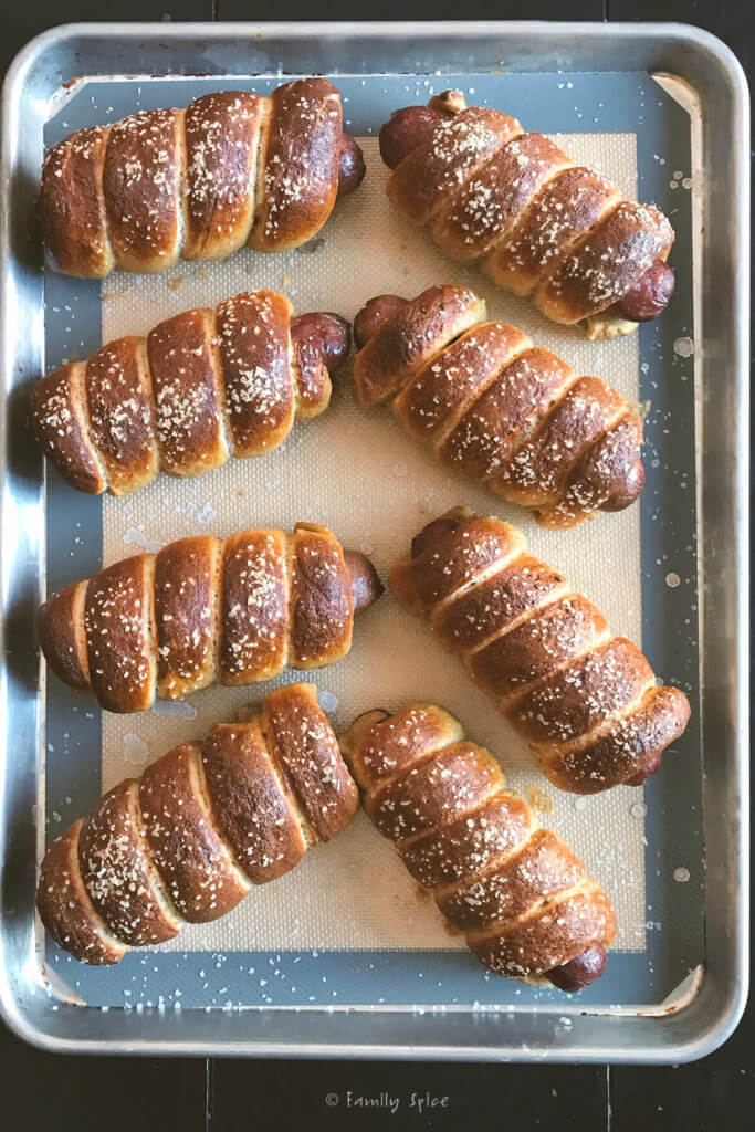 Top view of a baking sheet with freshly baked whole wheat pretzel dogs
