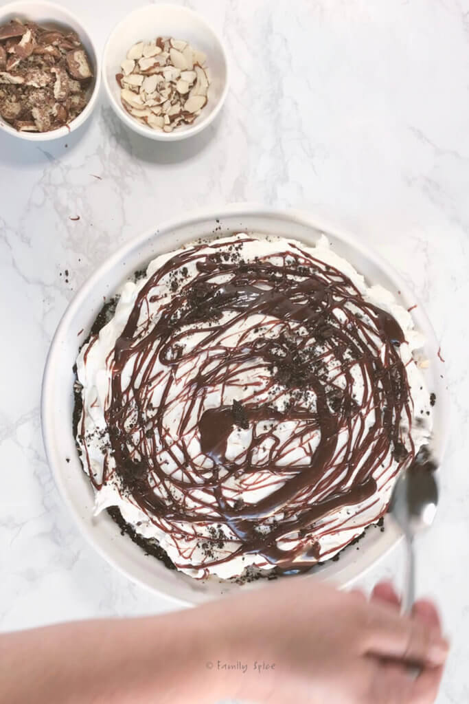 Fudge sauce drizzled over whipped cream topping of a mud pie