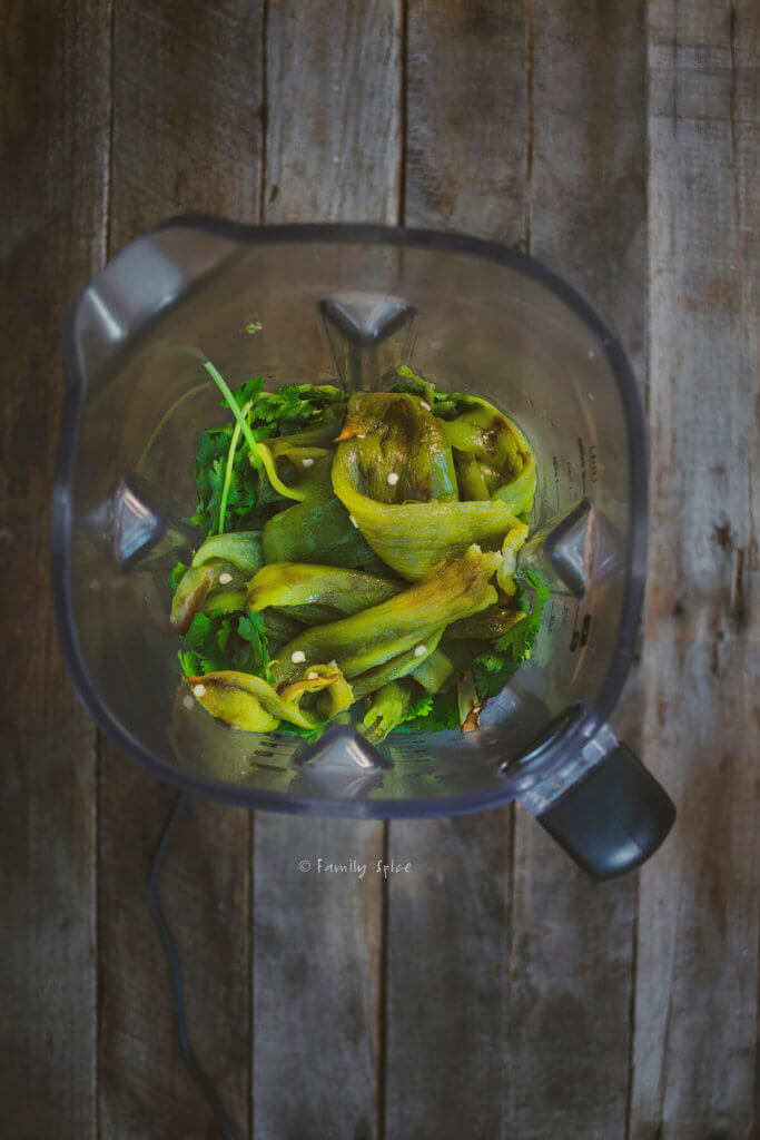 A blender with roasted chiles, onions, tomatillos and cilantro to make chili verde sauce