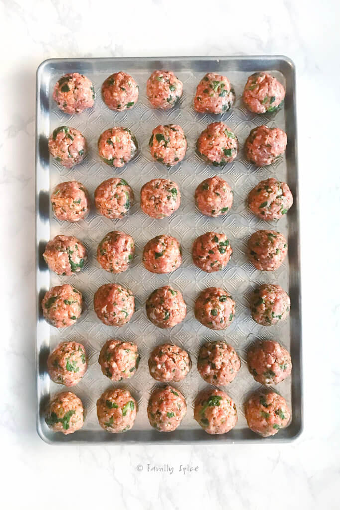 A baking sheet filled with meatballs ready to be baked