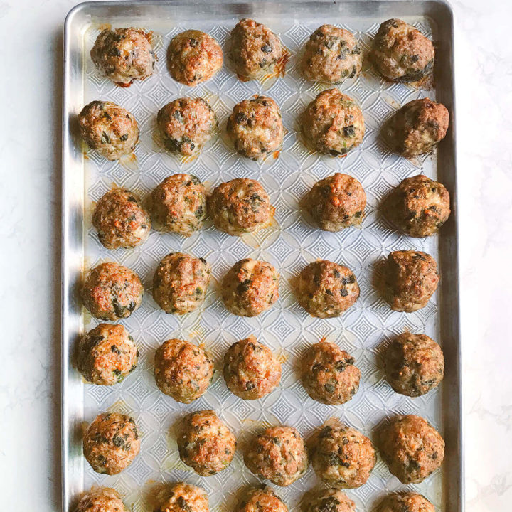 A baking sheet filled with baked meatballs